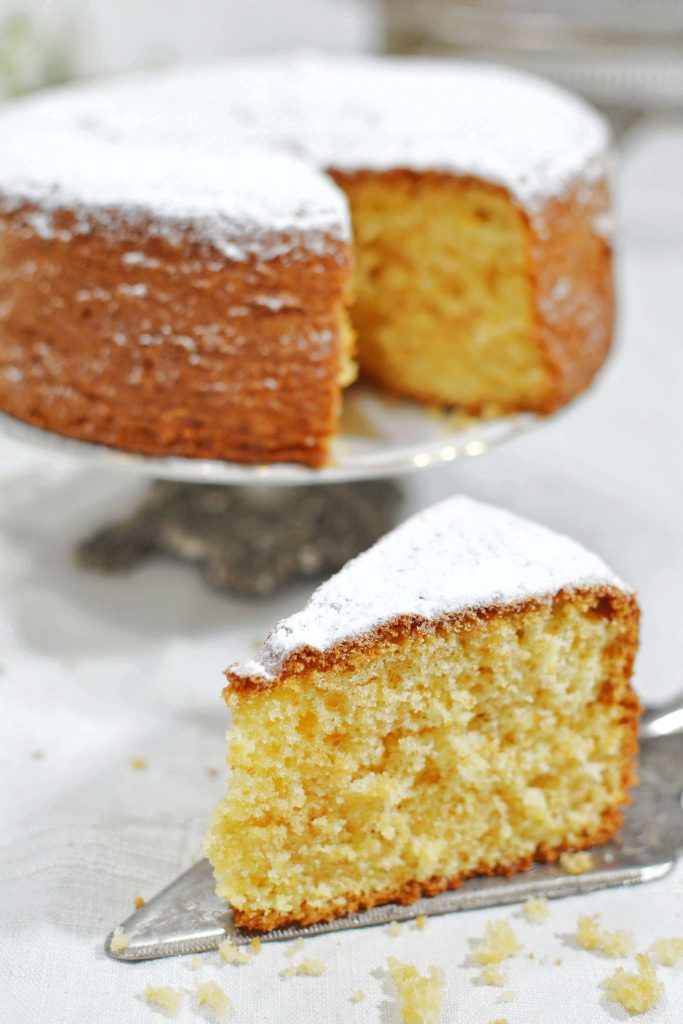 Torta alta su alzatina con fetta visibile, sfondo verticale