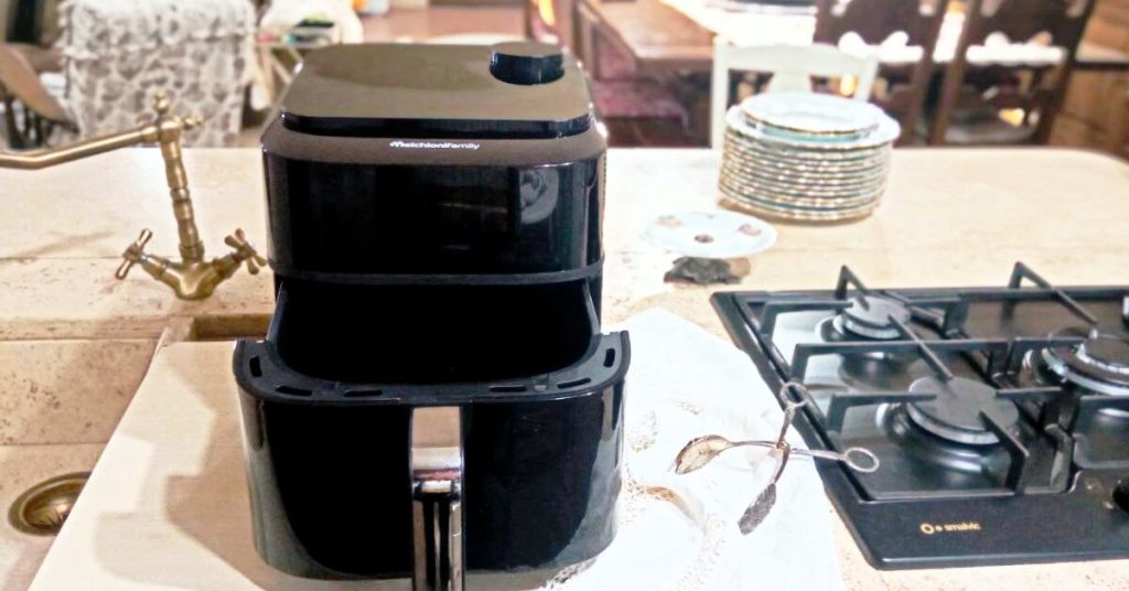 Friggitrice ad aria Melchioni Chiara su piano cucina in ambiente rustico, con cassetto aperto e accessori da cucina