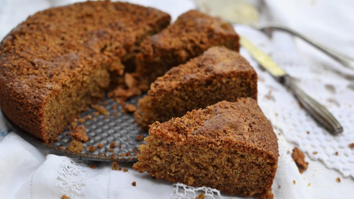 Torta alle Nocciole soffice senza burro – RicetteSOS. Torta rustica tagliata a spicchi su tovaglia bianca con posate vintage