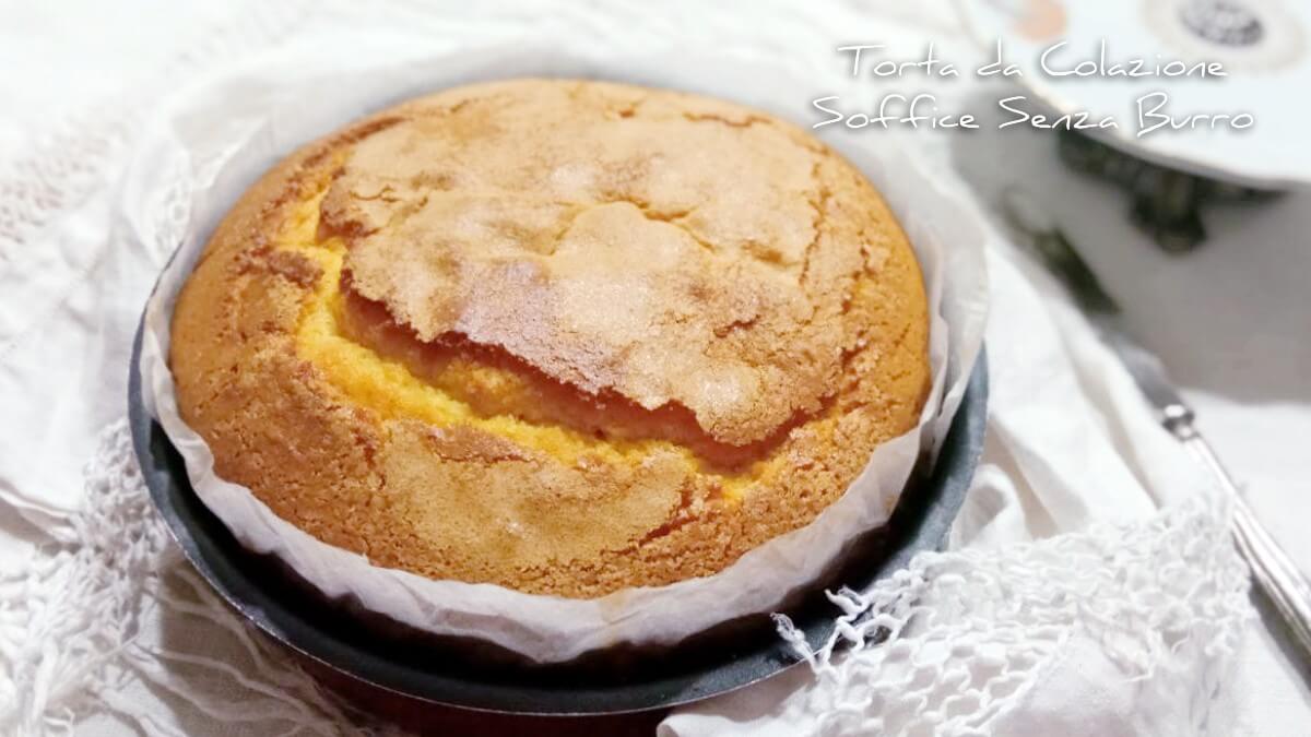 Torta soffice senza burro con crepette in superficie e carta forno visibile, pronta per essere servita